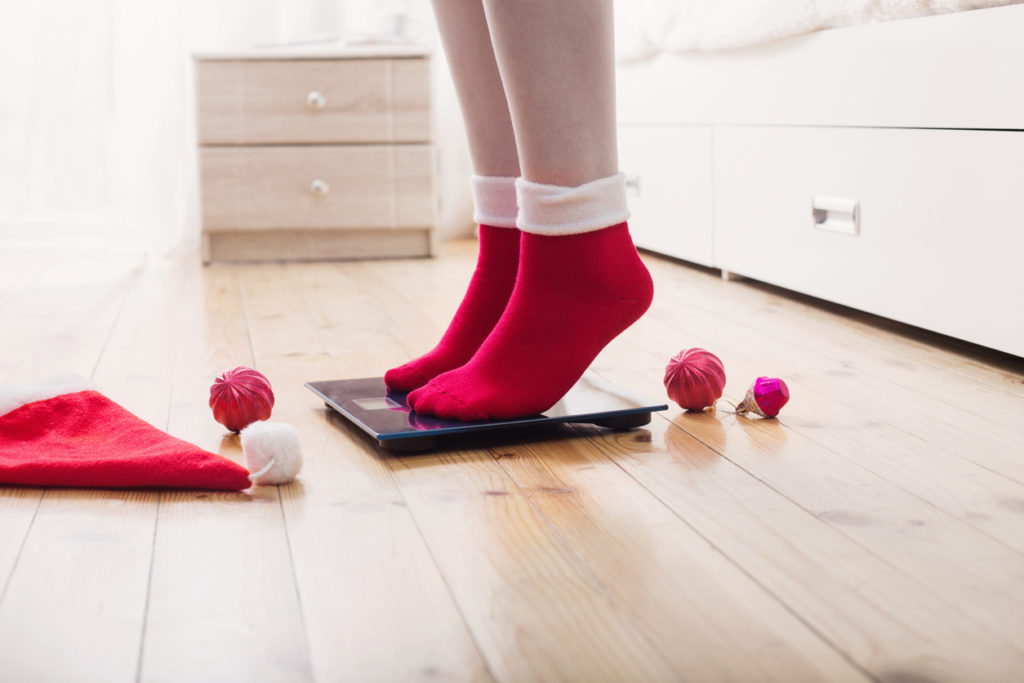 Are You 'Fed' Up With Twixtmas? 1 Female Feet Standing On Electronic Scales For Weight Control In Red Socks With Christmas Decoration